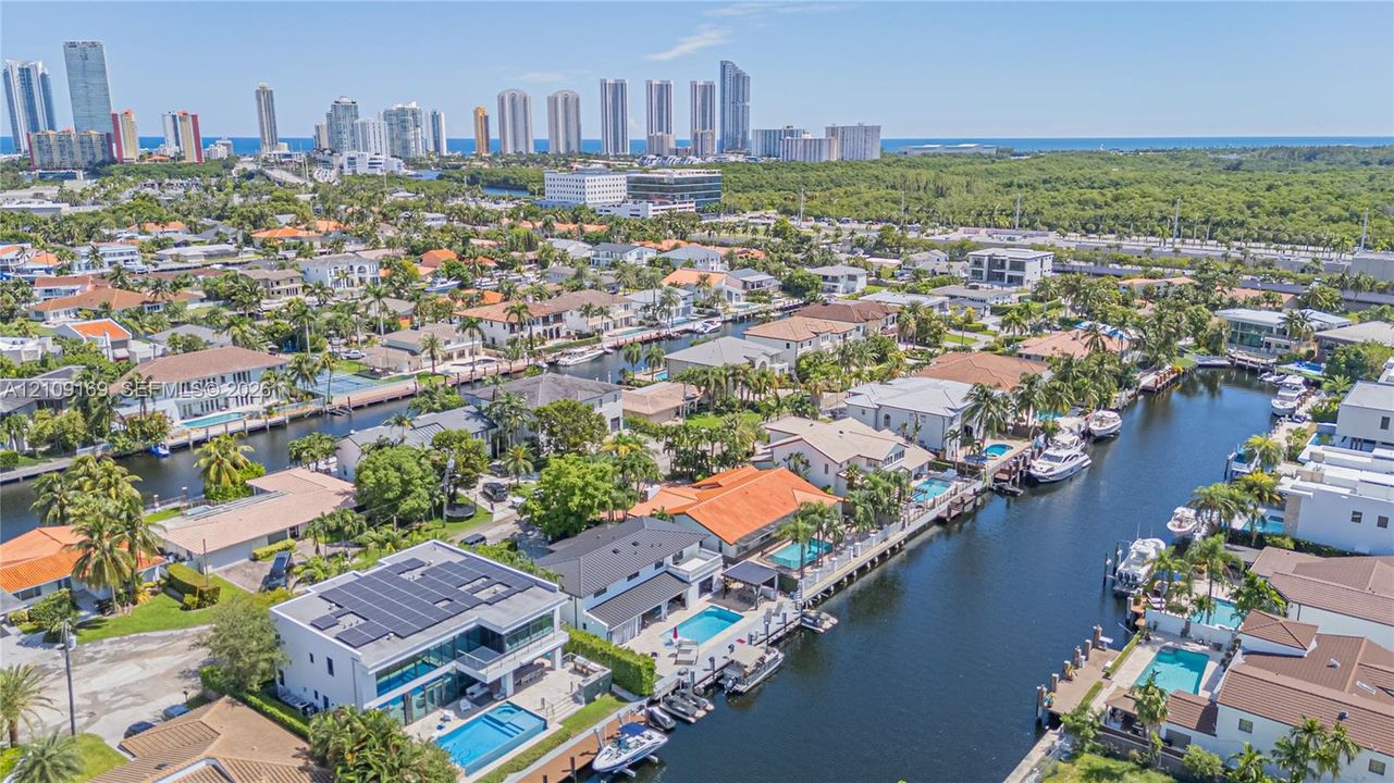 Aerial perspective featuring waterfront property with direct canal access, private boat dockage, and rooftop solar panel installation