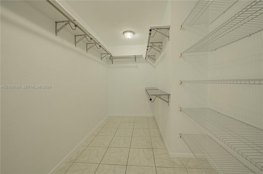 Walk-in storage space featuring ceramic tile flooring, multi-level wire shelving, and a centralized ceiling-mounted light fixture