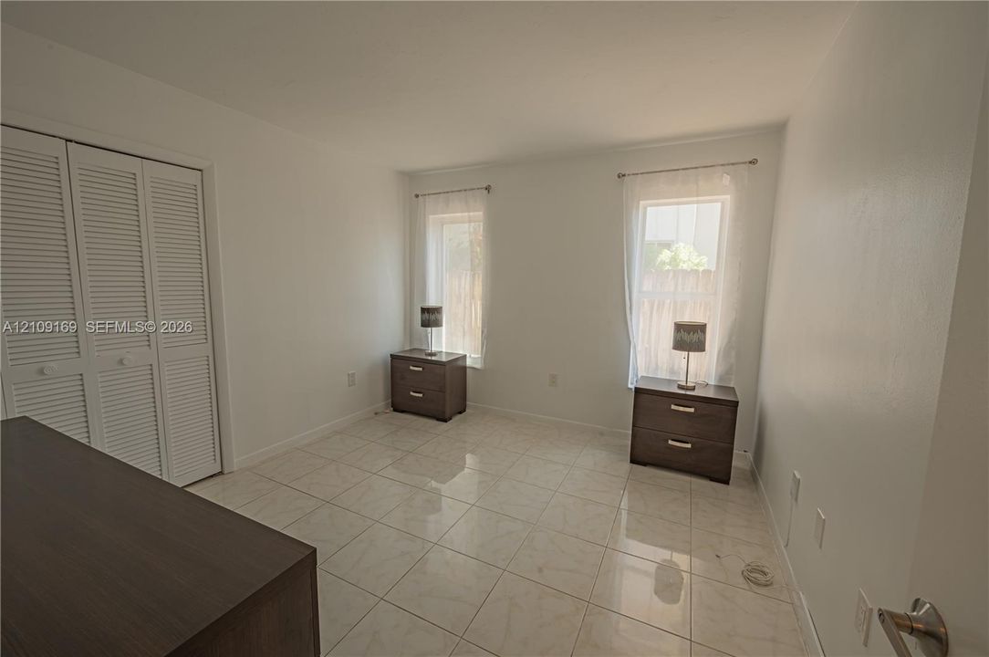 Interior space featuring large-format ceramic tile flooring, neutral walls, and a built-in closet with louvered double doors