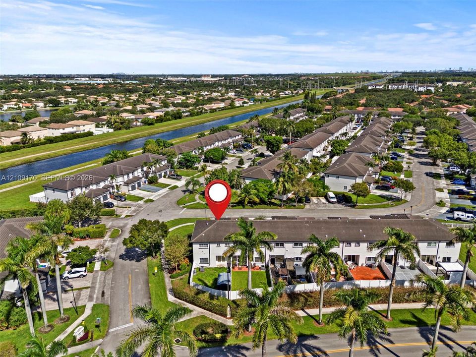 Aerial perspective featuring multi-unit residential architecture, shingle roofing, private fenced rear lawns, and mature palm landscaping within a planned community