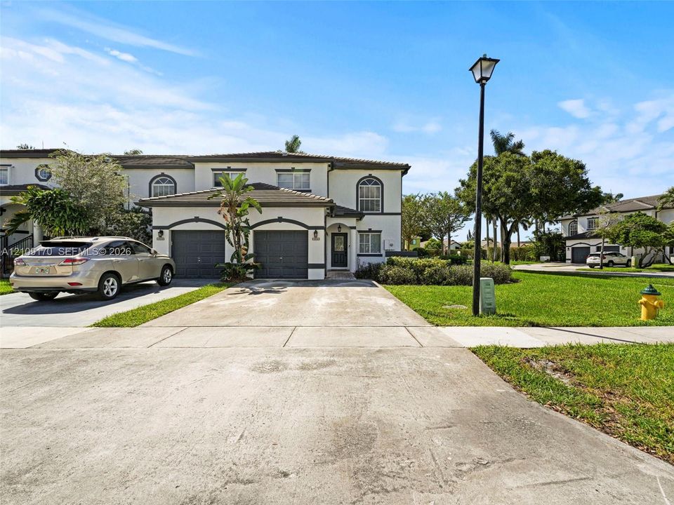 Two-story exterior featuring a stucco facade, arched entryway, concrete driveway, and an attached two-car garage