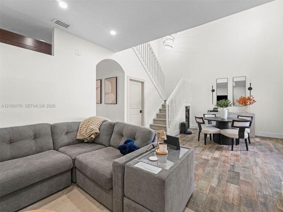 High ceilings, wood-finish flooring, staircase with white railing, and architectural archway