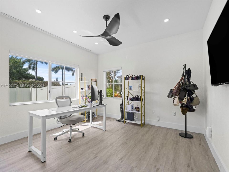 Room featuring wood-finish flooring, recessed lighting, and a multi-blade ceiling fan, with white-frame windows
