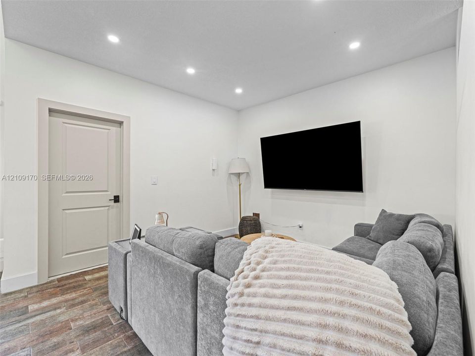 Interior room featuring wood-finish flooring, recessed lighting, and a multi-panel door with matte black hardware