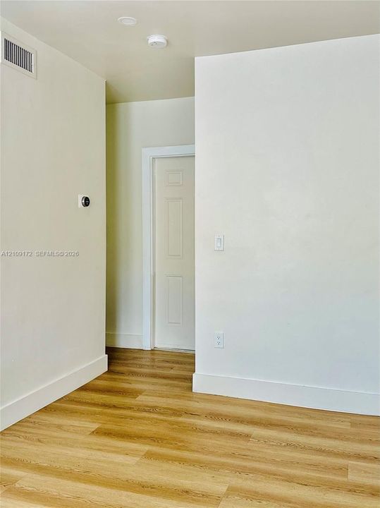 Interior space featuring wood-finish flooring, a neutral wall palette, and a four-panel interior door