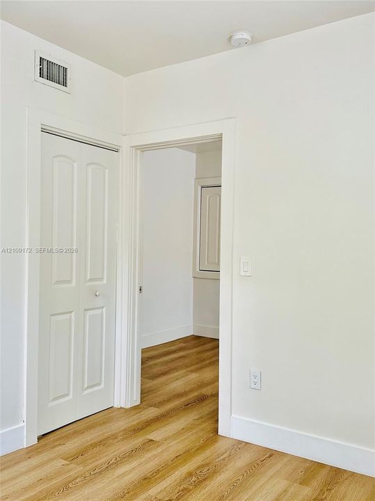 Wood-finish flooring throughout, interior doorway with classic trim, and bi-fold closet door