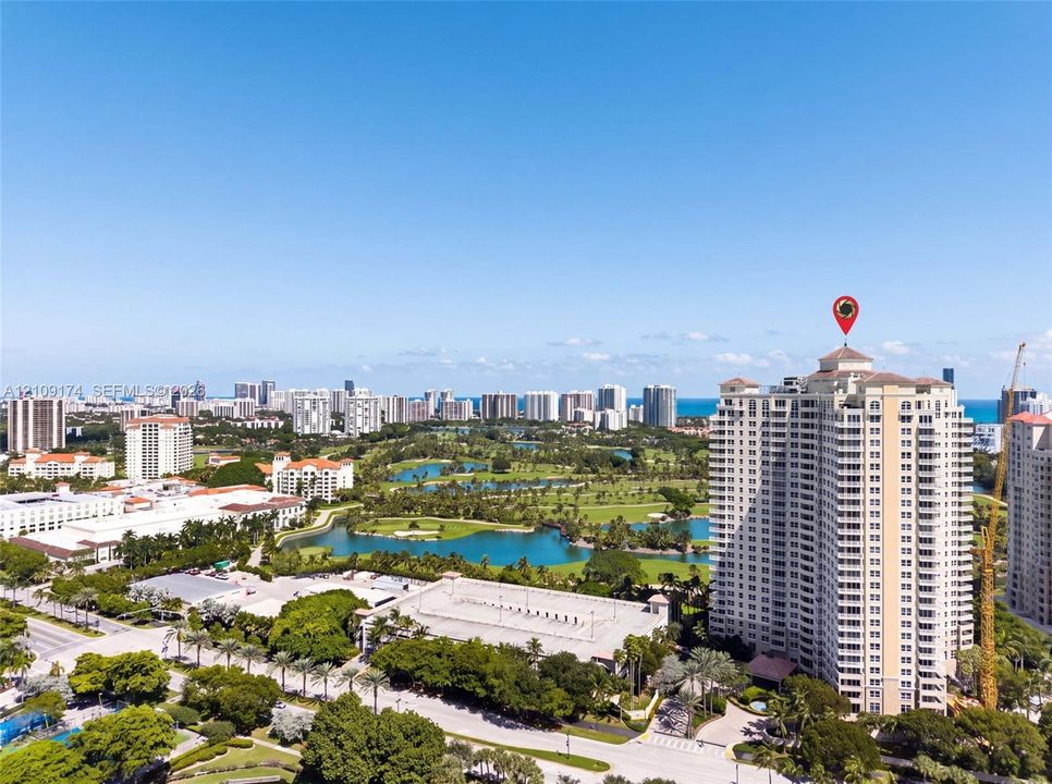 High-rise residential tower featuring a tiered architectural design, situated within a coastal metropolitan area with surrounding water features and integrated green spaces