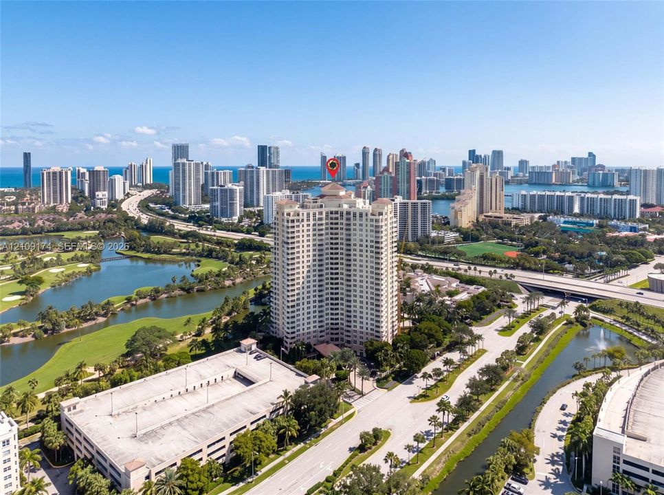 High-rise residential tower featuring a multi-story structural design, integrated parking facility, and surrounding water features