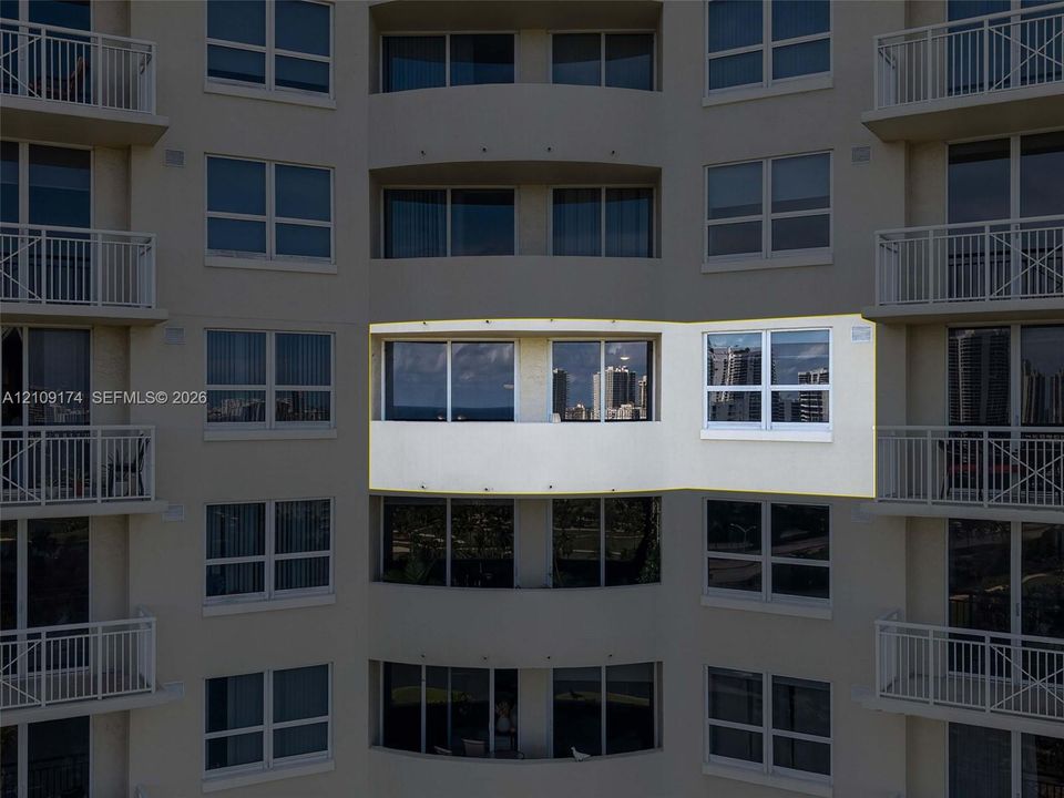 High-rise exterior featuring a recessed private balcony with glass sliding doors and dual-pane windows