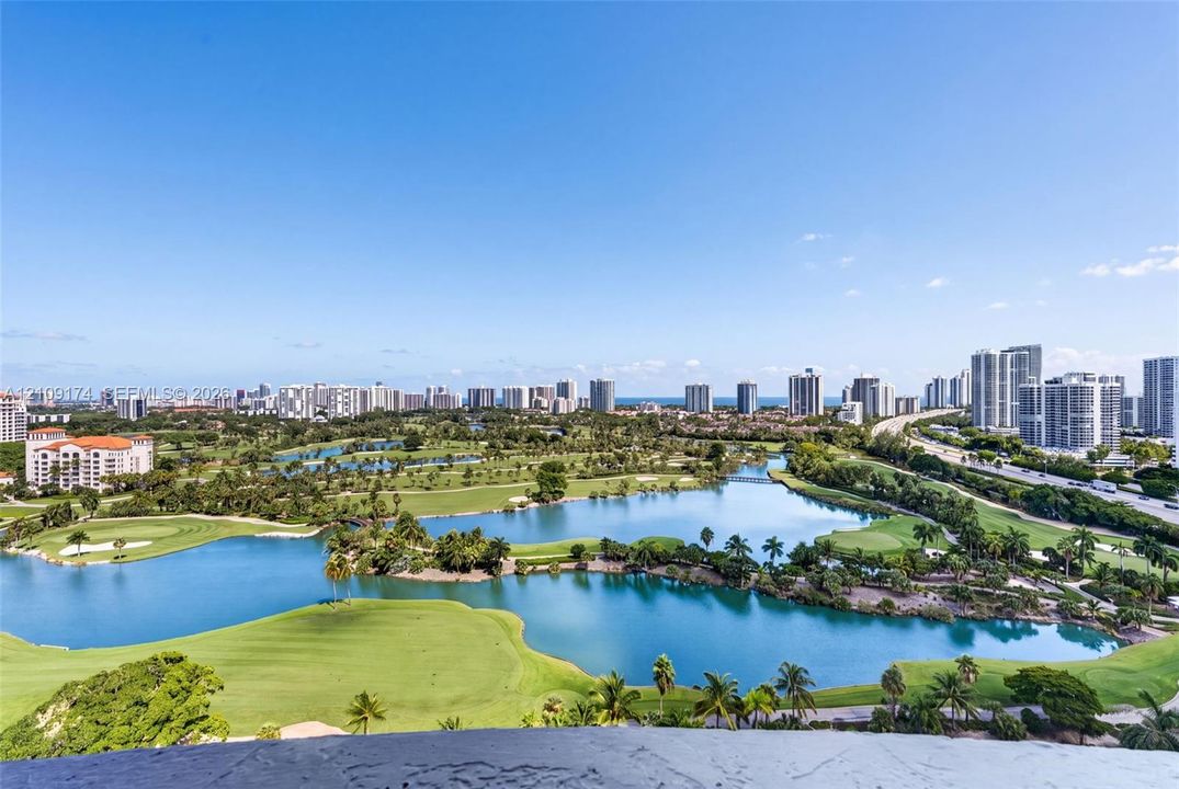 Panoramic scenery featuring a golf course, expansive lakes, and a metropolitan skyline