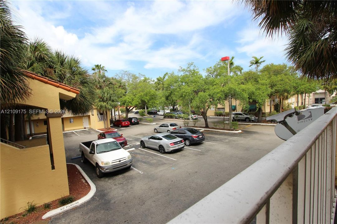 Paved parking lot featuring lined spaces, stucco exterior walls, and mature landscaping