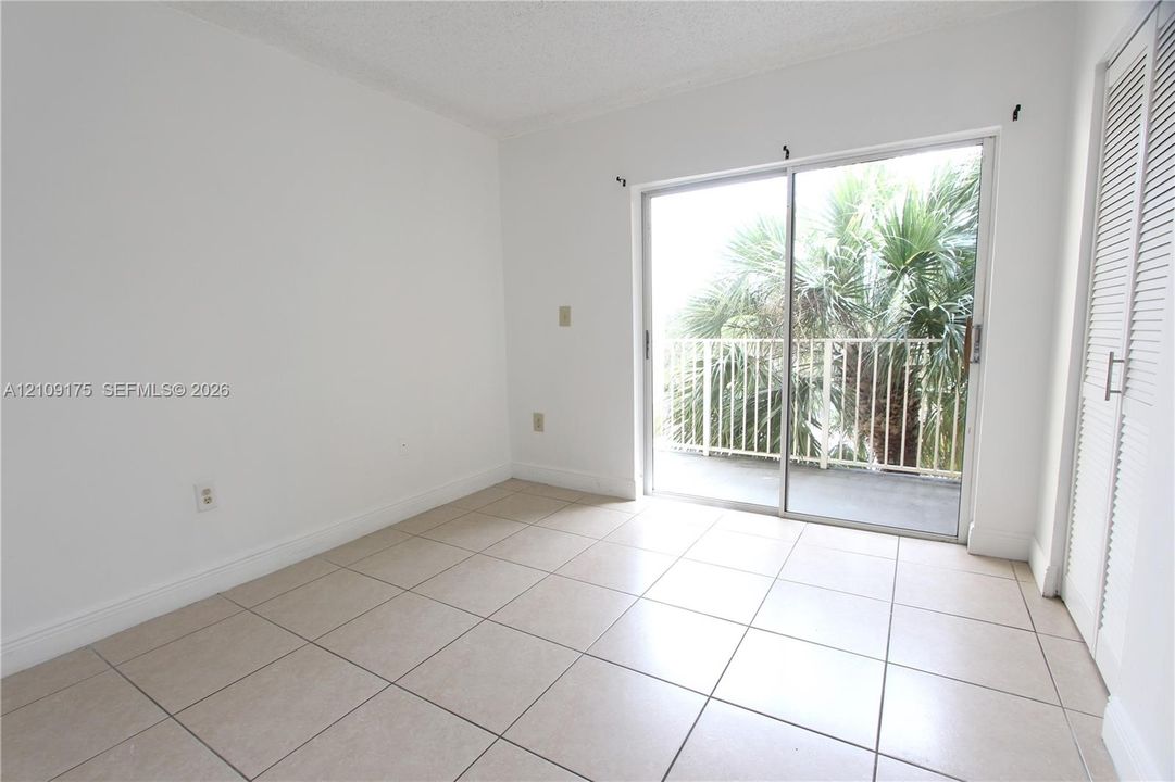 Ceramic tile flooring, sliding glass door with access to a balcony, and louvered-panel closet doors