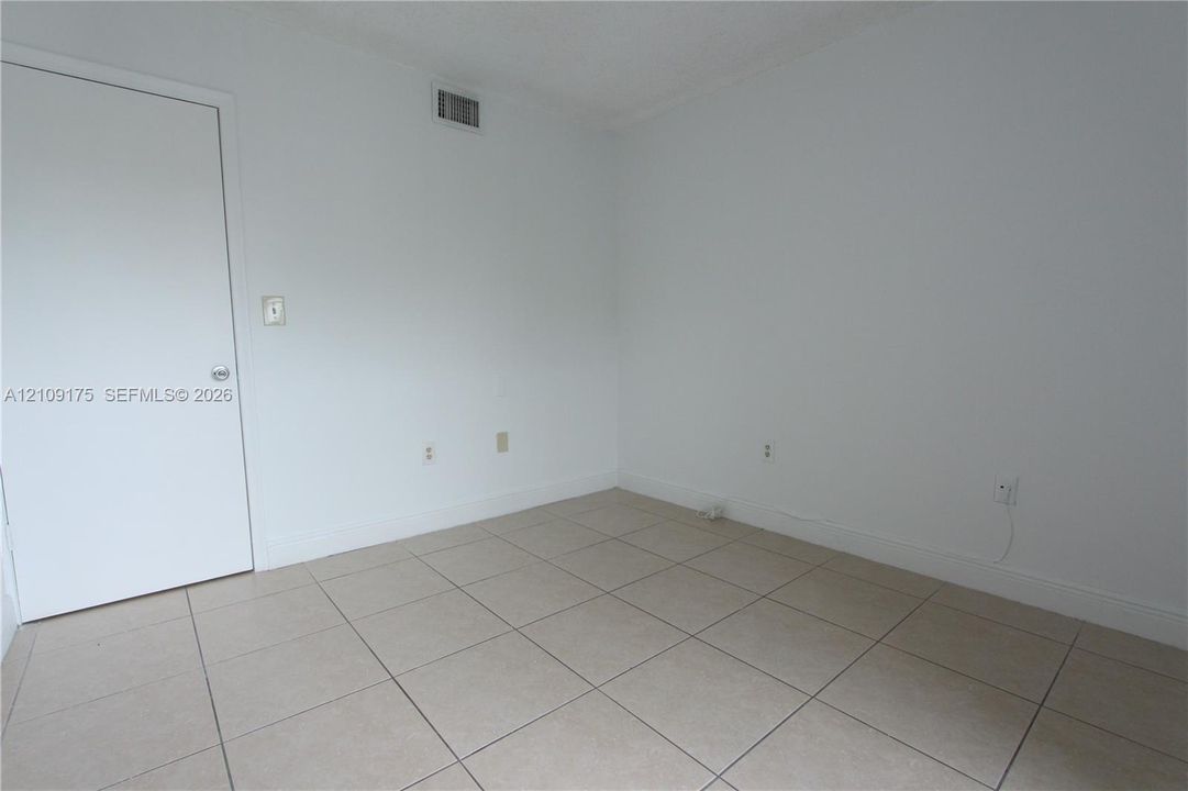 Room featuring neutral wall finishes, large-format tile flooring, and a solid-core interior door
