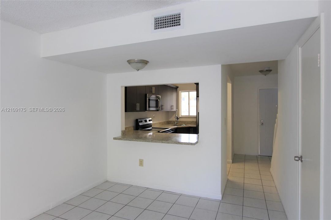 Kitchen featuring dark cabinetry, stone-surface countertop with bar seating, and stainless steel microwave