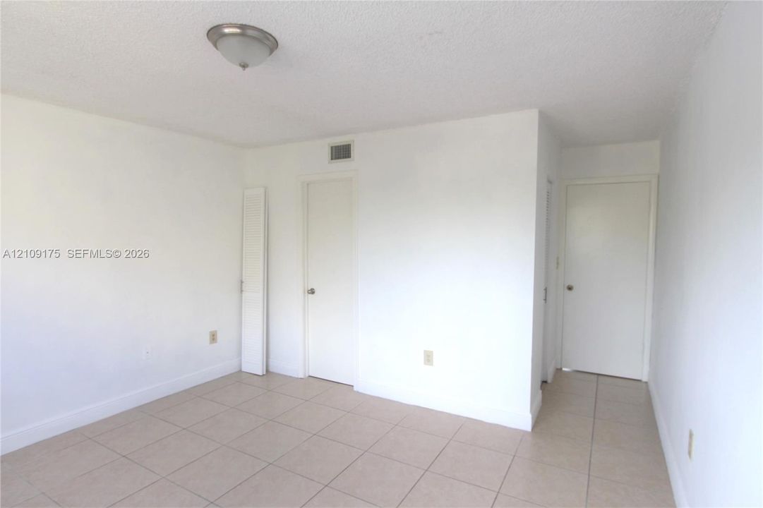 Neutral-toned tile flooring, semi-flush mount dome ceiling lighting, and multiple solid-core interior doors