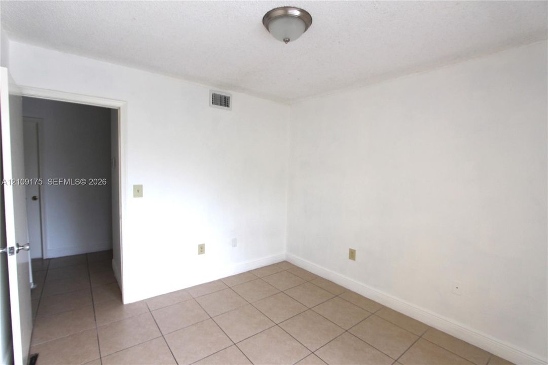 Neutral-toned ceramic tile flooring and ceiling-mounted flush light fixture