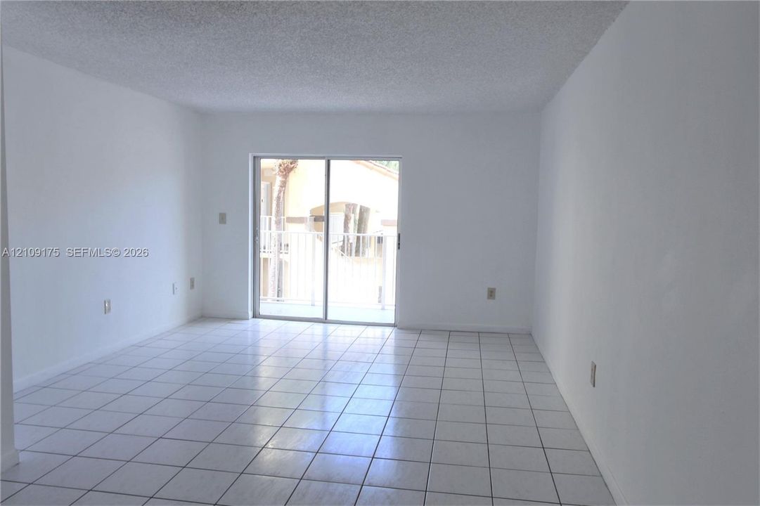 Interior space featuring white walls, large-format tile flooring, and a sliding glass door providing external access