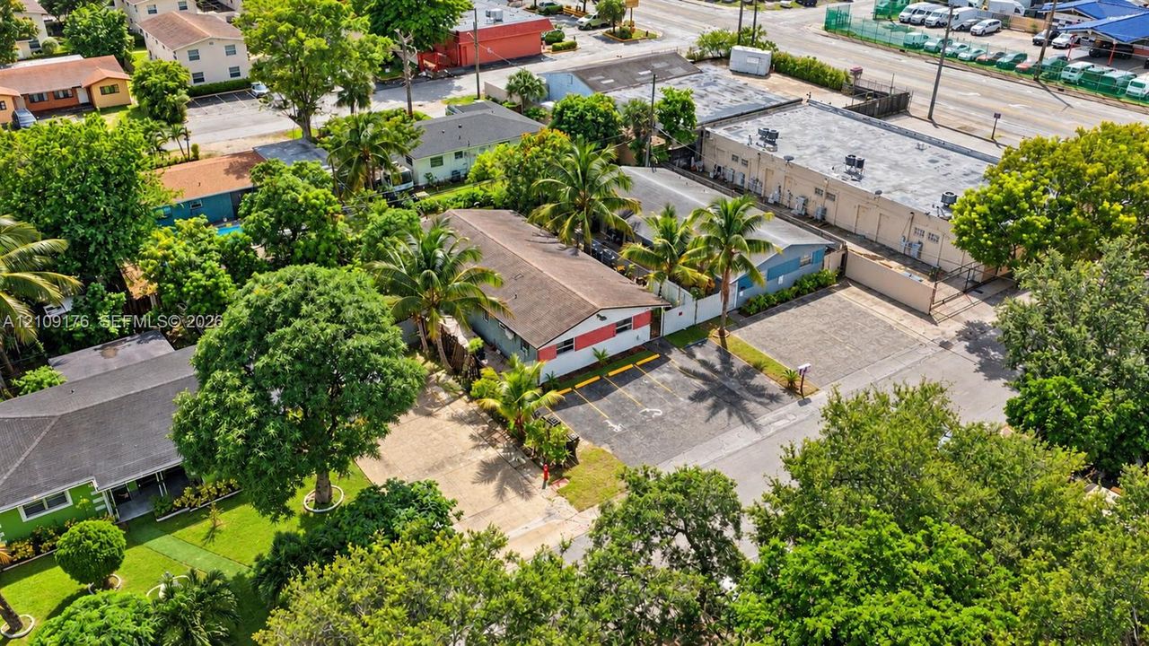 Single-story structure featuring a pitched roof, exterior masonry facade, paved off-street parking area, and mature palm landscaping
