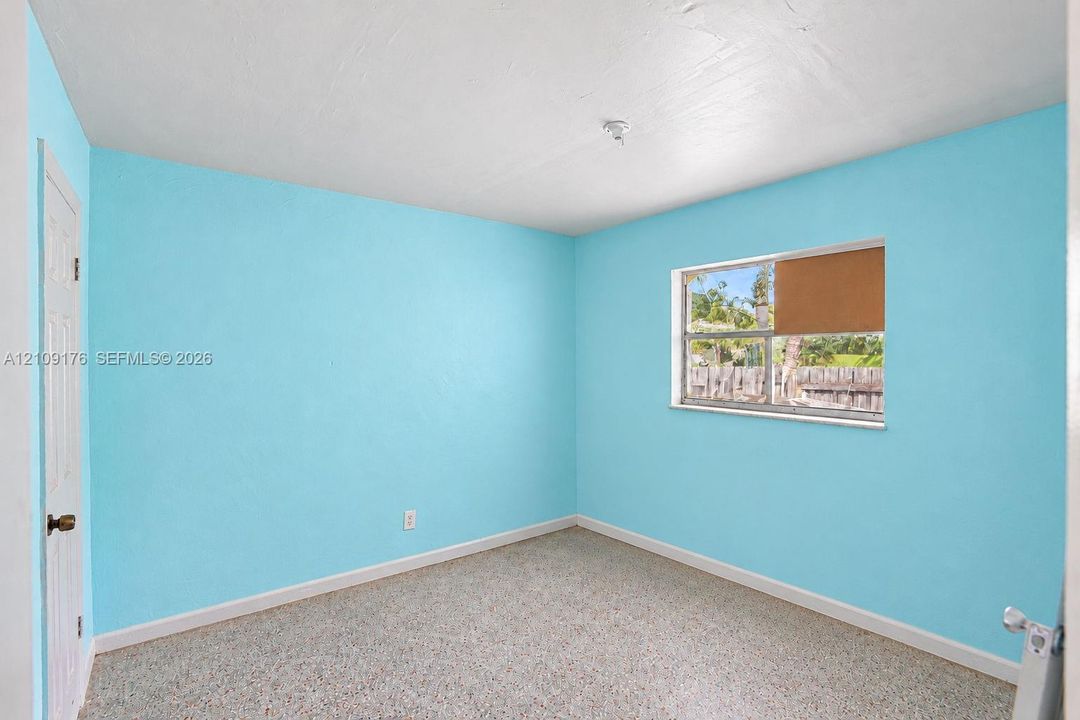 Interior room featuring terrazzo flooring, a sliding window with a horizontal blind, and a six-panel door
