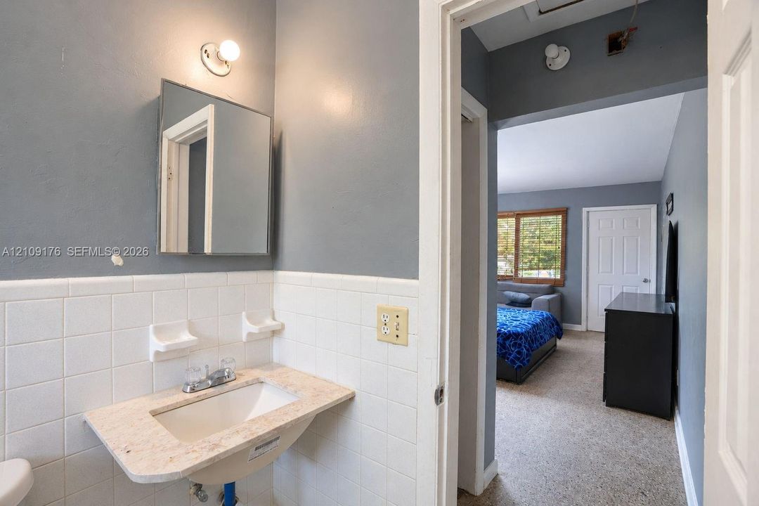 Wall-mounted vanity with a stone-finish countertop, integrated sink, and white ceramic tile backsplash featuring built-in soap dishes