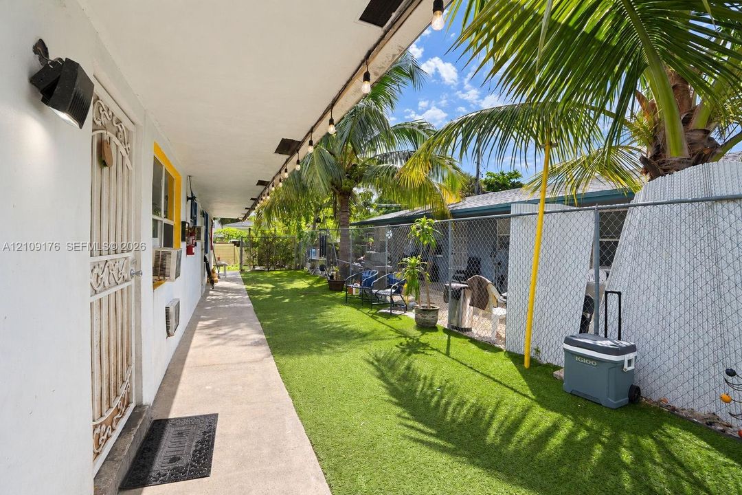 Covered concrete walkway featuring string lighting and metal security door