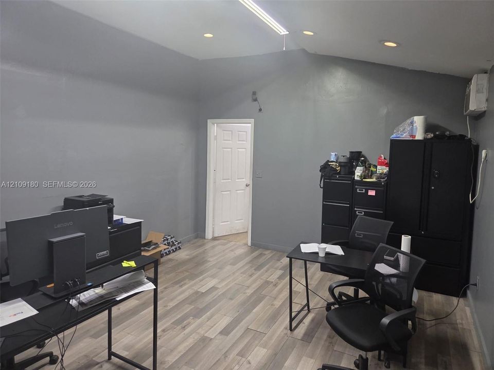 Interior space featuring vaulted ceilings, recessed lighting, wood-finish flooring, and a six-panel interior door