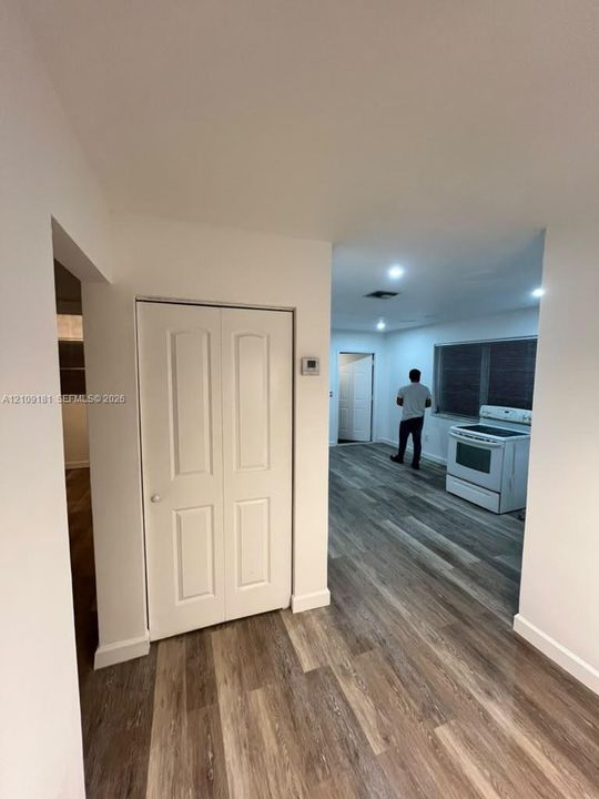 Wood-finish flooring throughout, white bi-fold closet doors, recessed ceiling lighting, and a freestanding white range