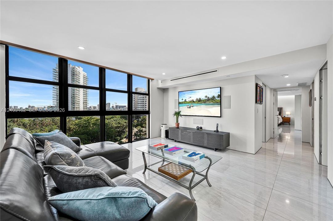 Living area featuring floor-to-ceiling windows, polished tile flooring, recessed lighting, and wall-mounted multimedia integration