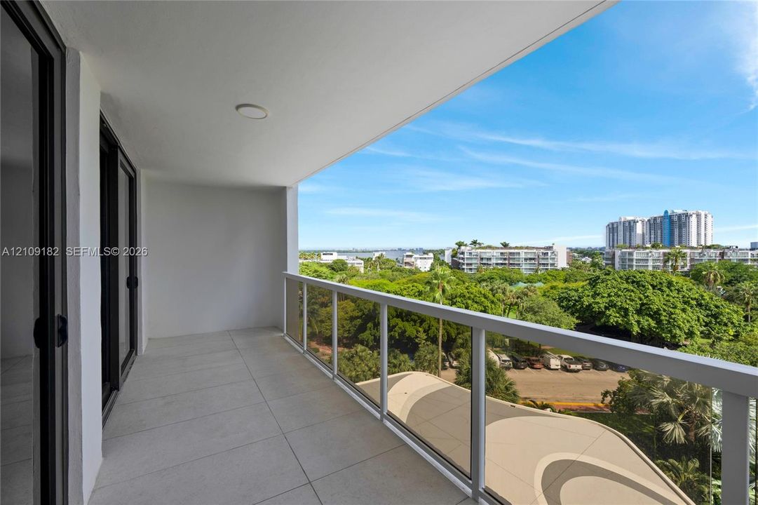 Covered balcony featuring tile flooring and a glass-paneled railing