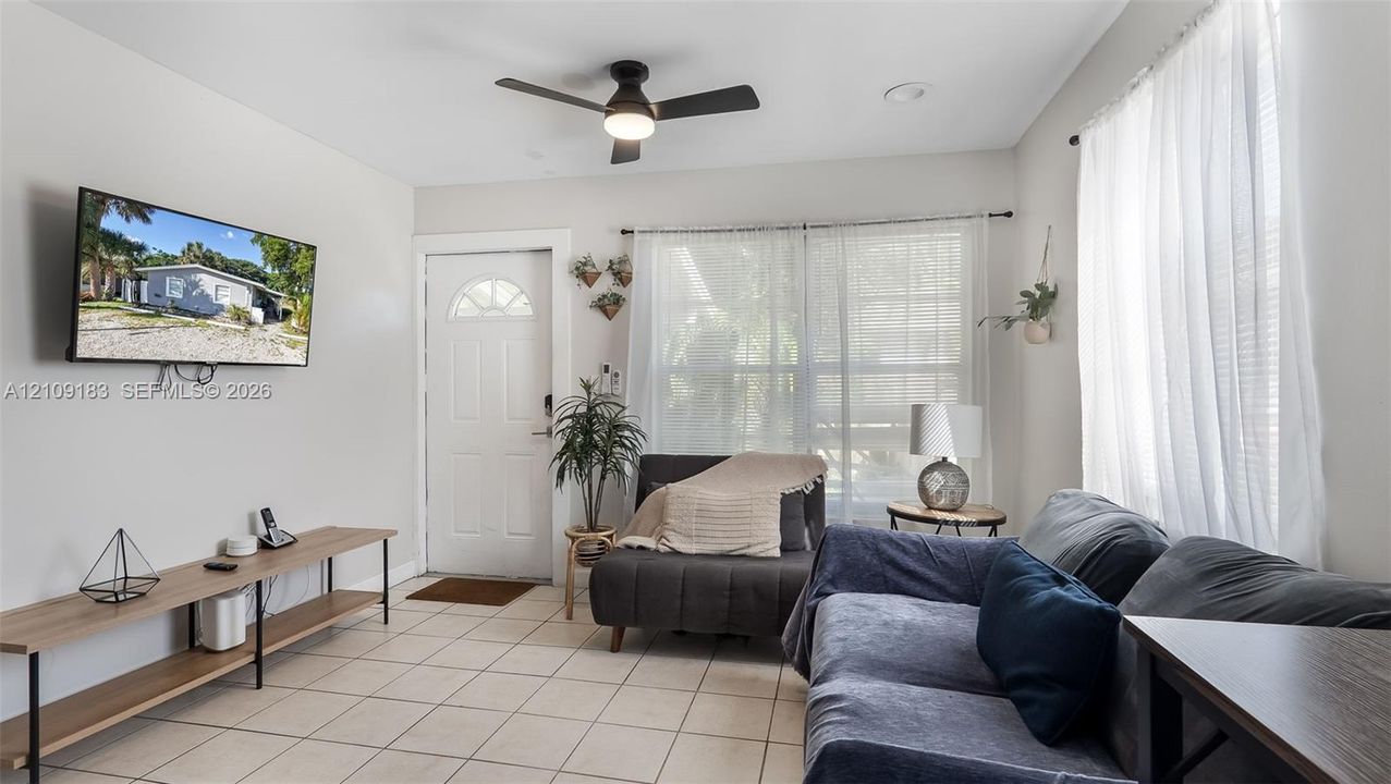 Interior space featuring neutral wall paint, large format tile flooring, a multi-paneled entry door, and a ceiling-mounted light fixture with a fan