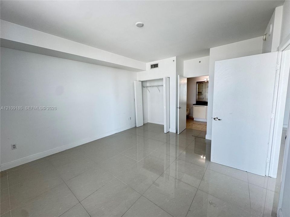 Neutral-toned tile flooring, built-in closet with shelving, and solid-core interior doors