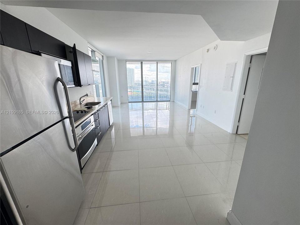 Kitchen area featuring dark cabinetry, stainless steel appliances, and tile flooring, highlighted by floor-to-ceiling windows