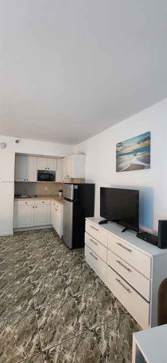 Kitchen area featuring white cabinetry, a built-in microwave, and stone-patterned tile flooring
