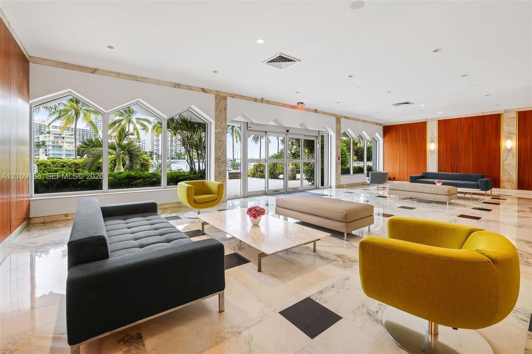 Lobby featuring stone tile flooring with decorative inlay, floor-to-ceiling multi-panel windows, wood-paneled walls, and recessed lighting