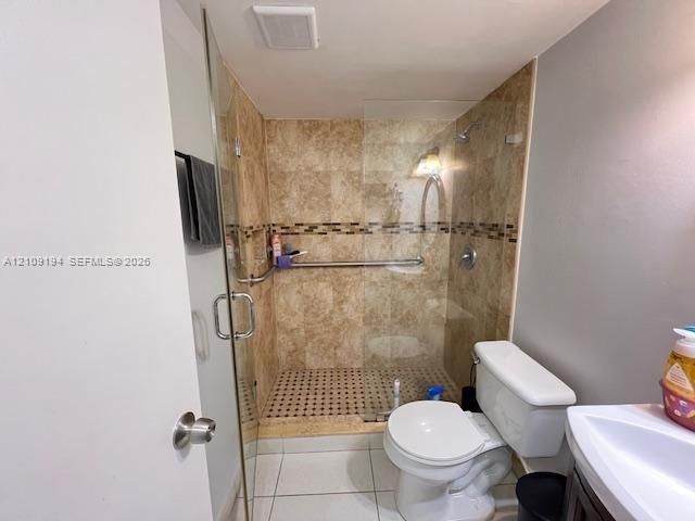 Walk-in shower with floor-to-ceiling stone-finish tile, glass enclosure, mosaic tile shower floor, and stainless steel grab bars