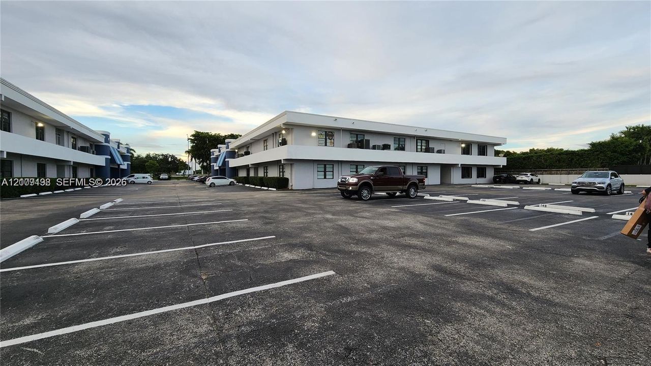 Multi-story building exterior featuring a paved parking area and marked surface parking spaces