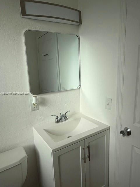 White vanity featuring a rectangular integrated sink, chrome dual-handle faucet, rounded rectangular mirror, and an overhead rectangular light fixture