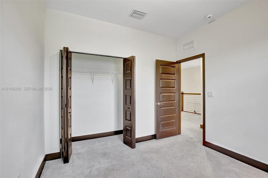 Neutral-toned wall finish featuring five-panel solid wood doors, folding closet doors, and high-pile wall-to-wall carpeting