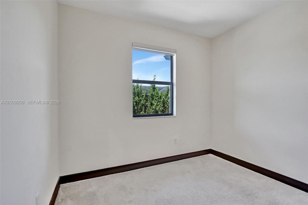 Neutral-toned wall finish, wall-to-wall carpeting, and a single-pane window with dark-toned trim
