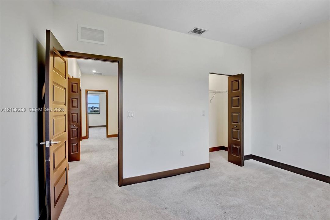 Neutral-toned wall-to-wall carpeting, solid-core four-panel interior doors, and built-in closet shelving
