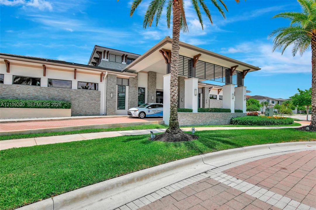 Modern exterior featuring stone veneer siding, covered entryway with structural columns, decorative wood-finish corbels, horizontal slat detailing, and a brick-paved driveway