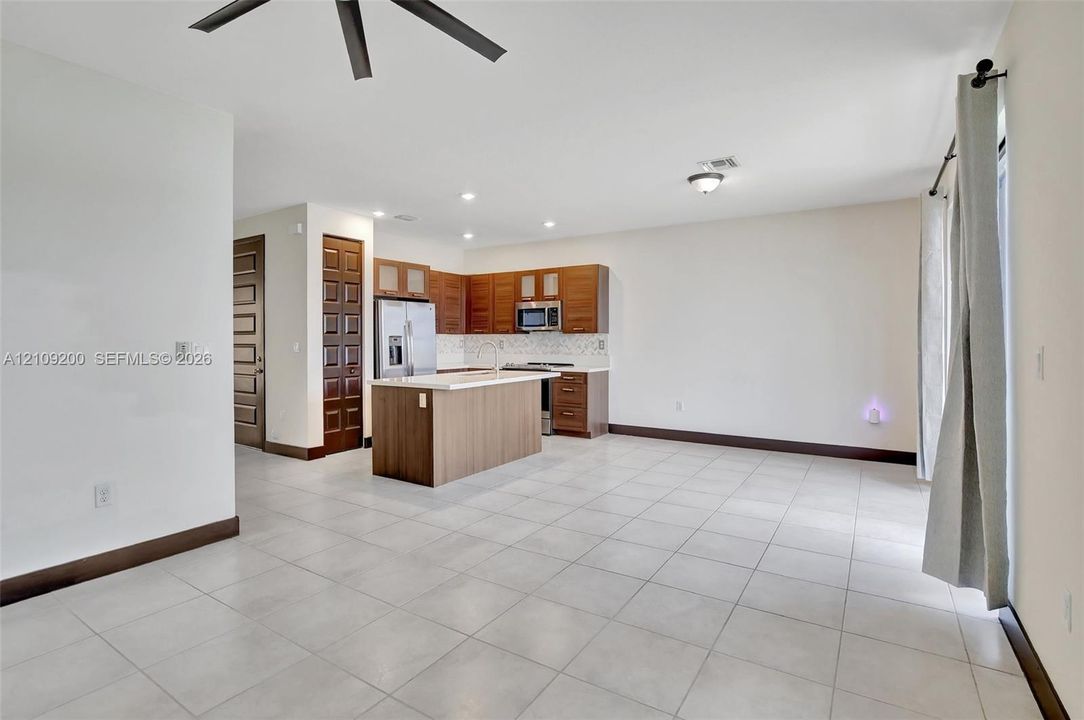 Kitchen featuring wood-finish cabinetry, a center island with light-toned surface, recessed lighting, tile flooring, and built-in stainless steel appliances