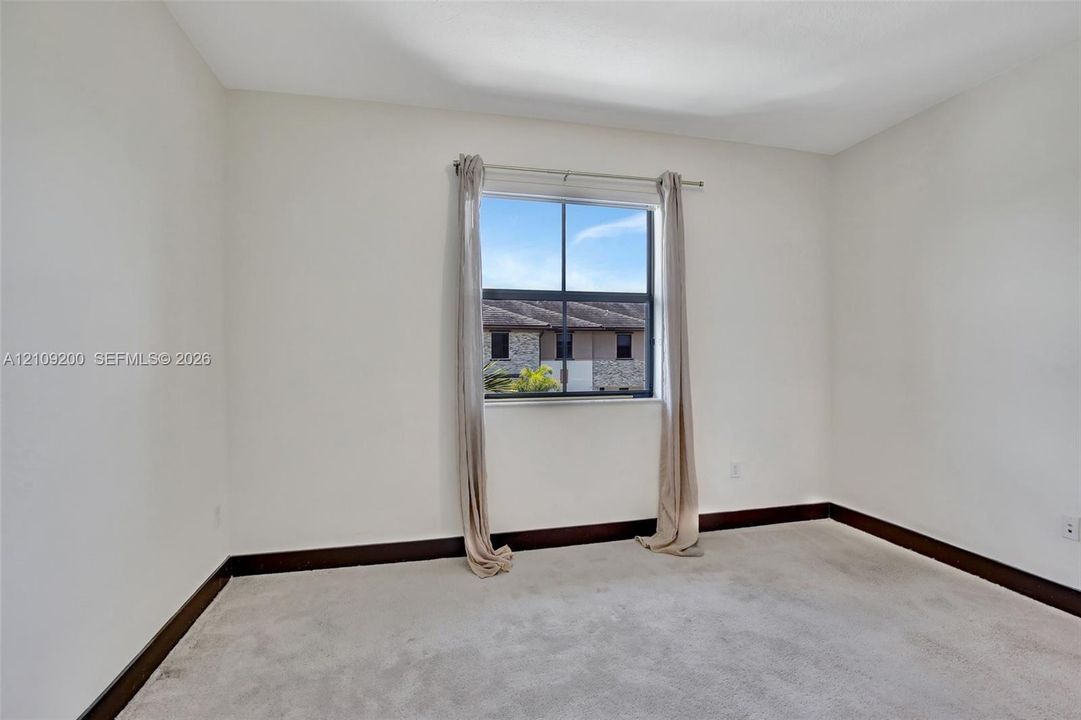 Neutral-toned carpeted room featuring a single window and dark wood-finish trim