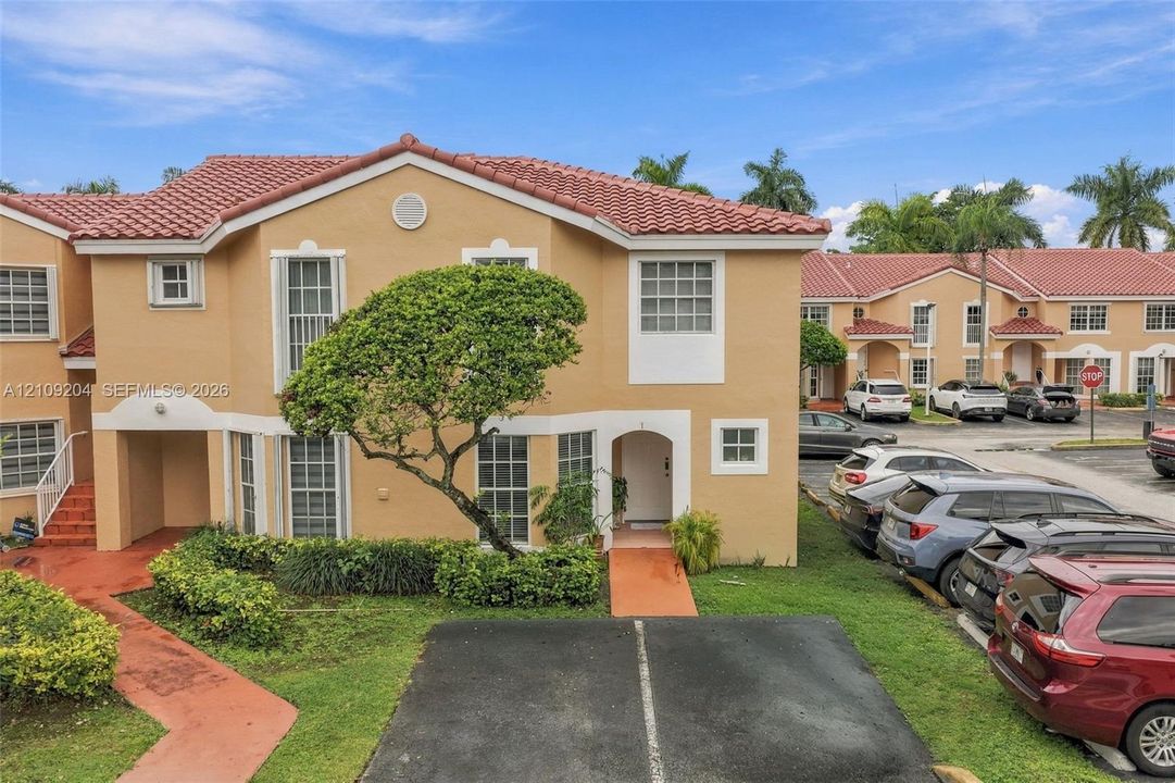 Stucco exterior featuring a mission-style clay tile roof, arched entryway, and dedicated surface parking