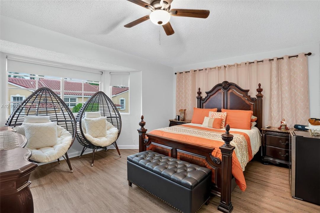 Wood-finish flooring, multi-pane bay window, and ceiling fan with integrated lighting