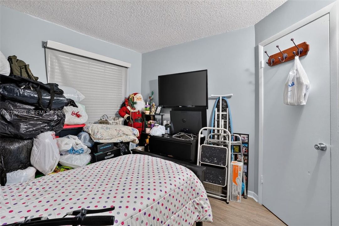 Room featuring wood-finish flooring, a neutral wall finish, and a window with fitted blinds