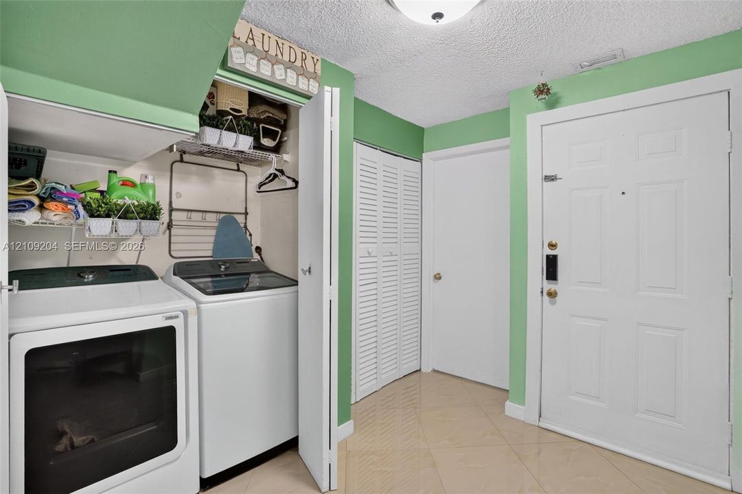 Utility area featuring built-in wire shelving, louvered closet doors, tiled flooring, and a six-panel exterior entry door