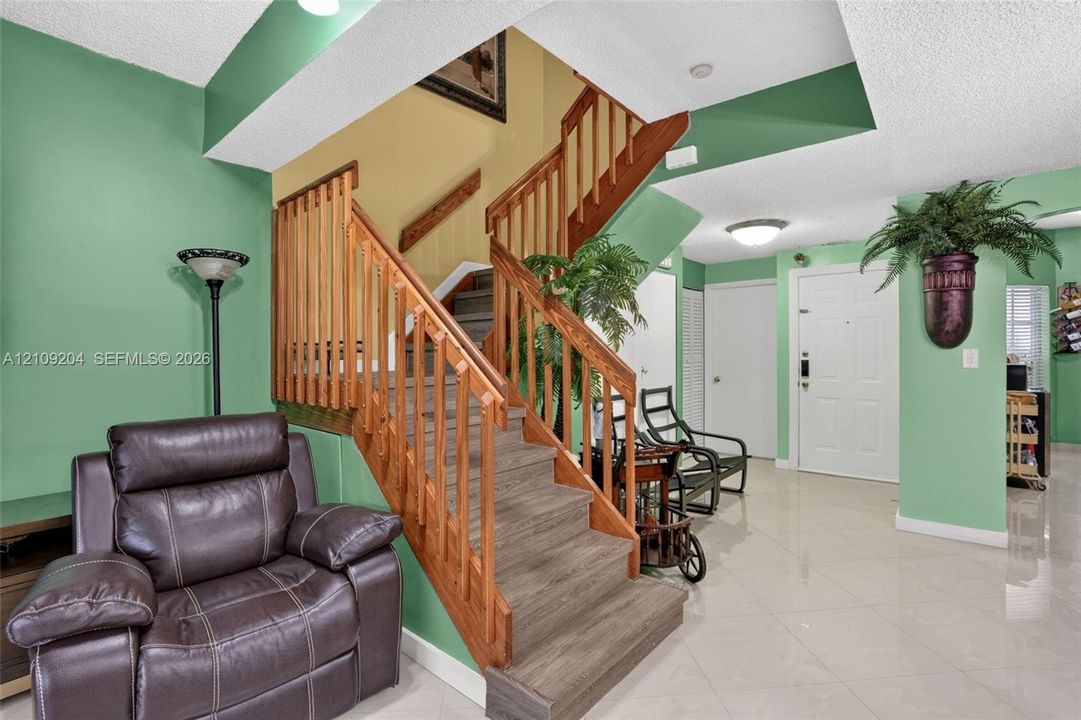 Foyer featuring tile flooring, staircase with wood-finish treads, and vertical wood balustrade