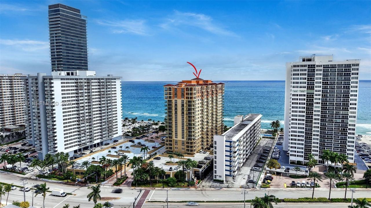 High-rise coastal condominium tower featuring multiple private balconies, a terracotta-style roofline, and direct proximity to the oceanfront