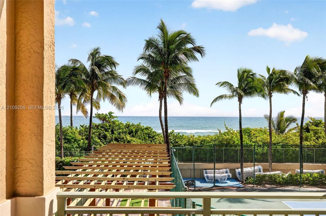 Outdoor terrace featuring a natural wood pergola, metal railing, and ocean backdrop